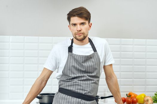 Man chef aprons kitchen preparing food restaurant vegetables on the table