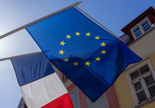 Flags of France and the European Union on the building against the blue sky on a bright Sunny day