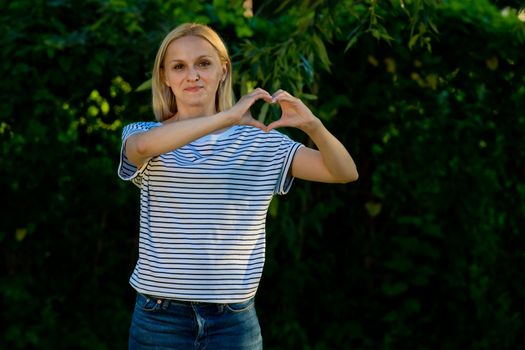 Young woman in jeans and a striped T-shirt posing in the garden.