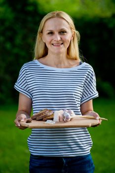 Young woman holding wooden board with garlic, lard and bread. Closeup.