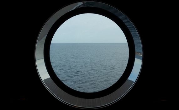Sea view through the porthole of a passenger ferry in cloudy, calm weather