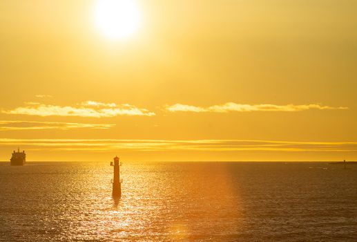 Lighthouse in the strait between the islands of the Stockholm archipelago, lit by the rays of the sun, in the early morning.