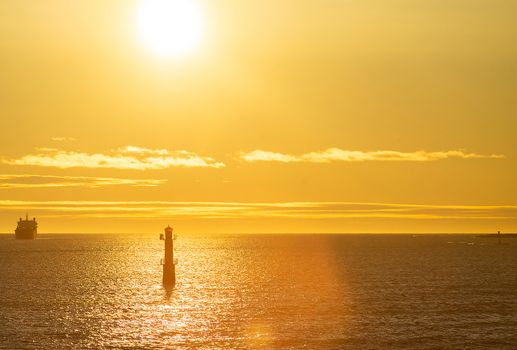 Lighthouse in the strait between the islands of the Stockholm archipelago, lit by the rays of the sun, in the early morning.