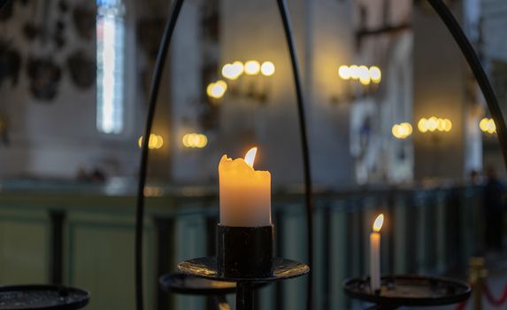 Burning candle on a metal candlestick in a Catholic Church
