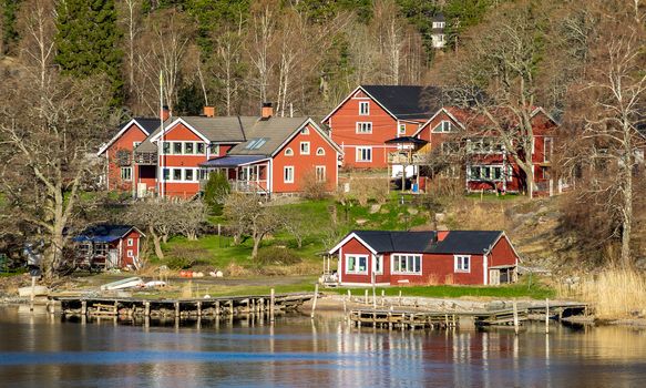 Picturesque summer houses painted in traditional falun red on dwellings island of the Stockholm archipelago in the Baltic Sea in the early morning.