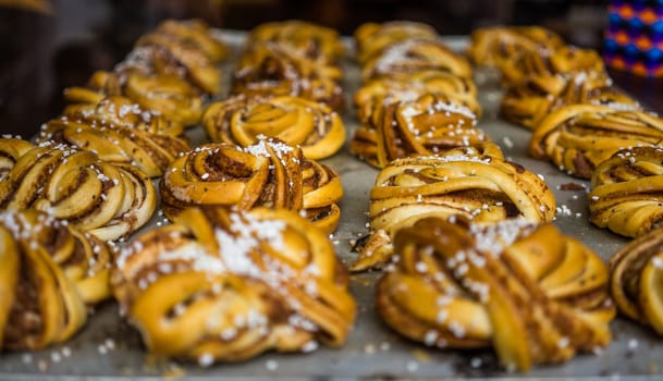 Fresh cinnamon rolls on a baking sheet in a pastry shop window.