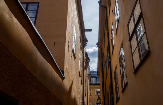 The narrow street of an old European city with yellow houses.
