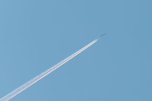 Jet passenger plane with reversing trail on a background of blue sky