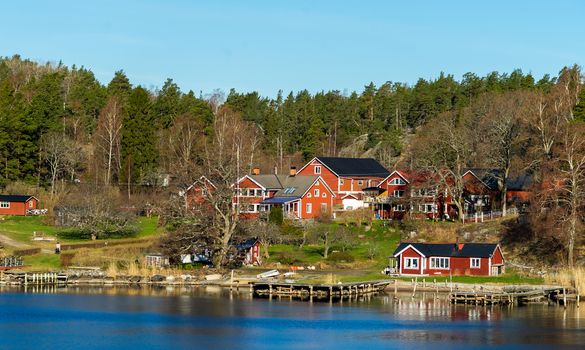 Picturesque summer houses painted in traditional falun red on dwellings island of the Stockholm archipelago in the Baltic Sea in the early morning.