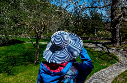 Girl in a wide-brimmed hat in a shady green park