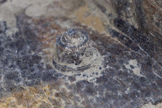 A corroded bolt nut and washer covered in dirt and rust