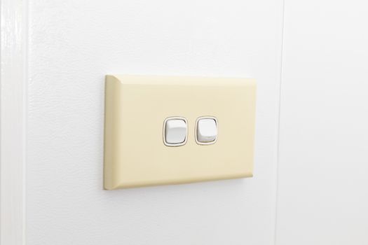 A double light switch on a white tiled wall