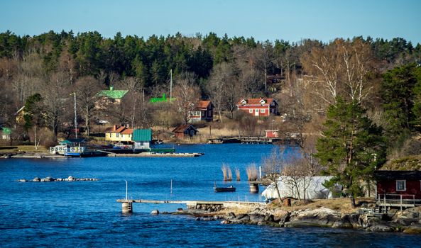 Picturesque summer houses painted in traditional falun red on dwellings island of the Stockholm archipelago in the Baltic Sea in the early morning.