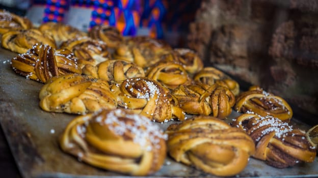 Fresh cinnamon rolls on a baking sheet in a pastry shop window.