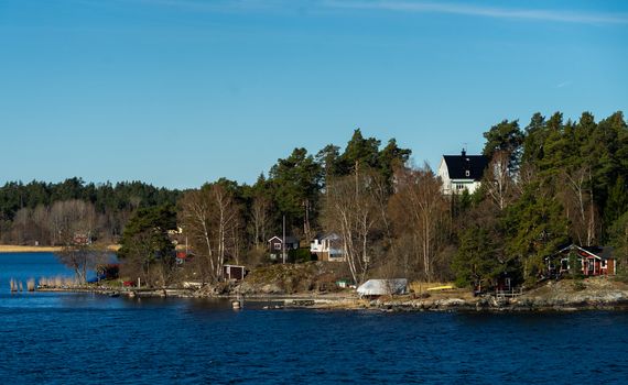 Picturesque summer houses painted in traditional falun red on dwellings island of the Stockholm archipelago in the Baltic Sea in the early morning.