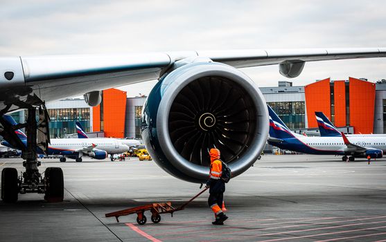 October 29, Moscow, Russia, Airport employee at the engine Rolls-Royce Trent XWB of a wide-body aircraft Airbus A350 XWB at Sheremetyevo Airport.