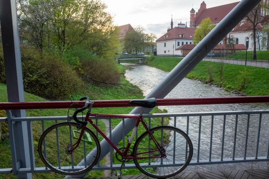 Road bike on the railing of a pedestrian bridge over a river in Vilnius.