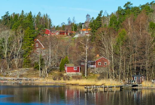 Picturesque summer houses painted in traditional falun red on dwellings island of the Stockholm archipelago in the Baltic Sea in the early morning.