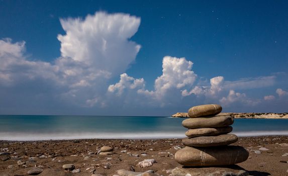 Pillars of stones on the sandy and pebble beach of the Mediterranean Sea, shot in calm weather at night with a long exposure.