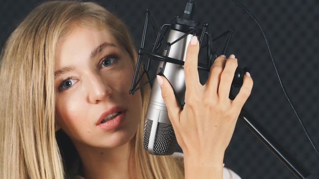 close up,  young Caucasian woman face and microphone. Female singer attractive Practice singing in the recording studio. 
concept Artist audition for media, music, and performance producer.