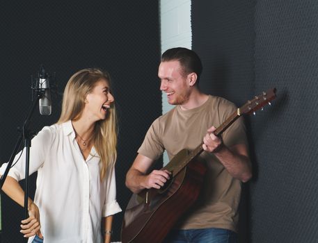 woman singer And man guitarist Caucasian people are practicing and Have fun laughing together in the sound recording studio. concept Artist audition for media, music, and performance producer.