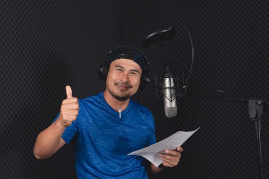 Confident Asian mature young man and a microphone Practice singing in the recording studio. Artist audition for media, music, and performance producer.