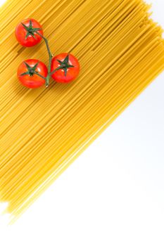 Uncooked spaghetti and cherry tomato on white background. Top view with copy space.