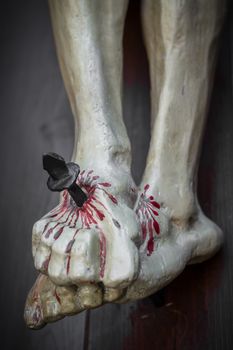 Closeup of feet of Jesus Christ nailed to the cross during the crucifixion. Shallow depth of field. Defocused blurry background.