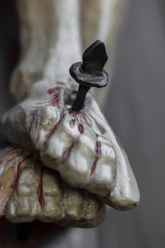 Closeup of feet of Jesus Christ nailed to the cross during the crucifixion. Shallow depth of field. Defocused blurry background.