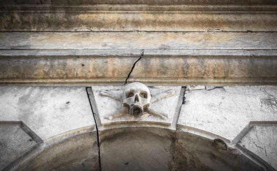A stone skull placed near the entrance of a charnel house, in an Italian graveyard.