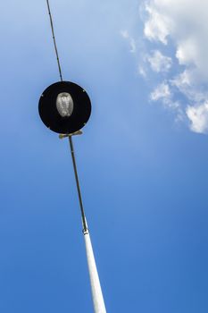 Street lamp supported by two electric cables, seen from below.