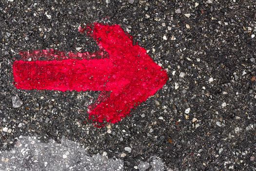 A red arrow pointing to the right, painted with red paint on the asphalt.