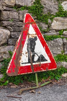 Old work in progress road sign with brick wall on background.