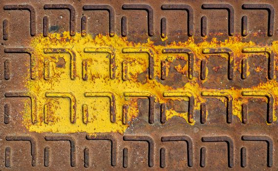 Relief pattern of rusty manhole cover in closeup with rust stain.