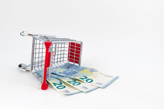 Small shopping cart with euros banknotes. Conceptual representation of wrong choice, error but also economic weight.