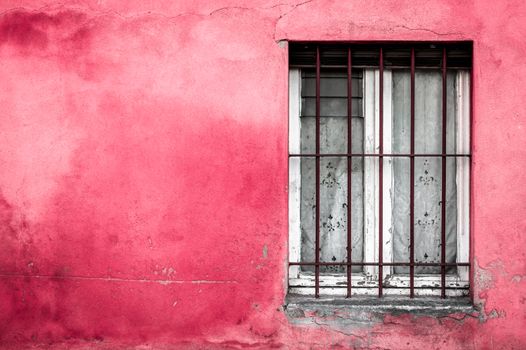 Old typical Mediterranean window on fuchsia stucco wall.