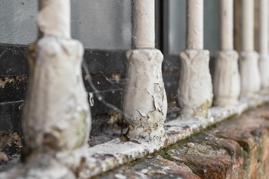Closeup of old window bars with peeling paint, dirt and cobwebs.