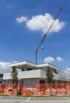 Modern building under construction against blue sky. Behind the crane.