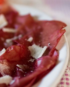 A plate of bresaola with parmesan cheese, olive oil and pepper.