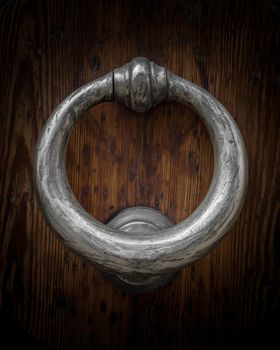 Old brass knocker on wooden door.