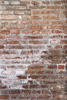 Details of the surface of an old wall in stones brown and red.