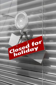 Sign saying "Closed for holiday" on a glass door with a white, closed venetian blind. It can be used for business concepts or backgrounds.