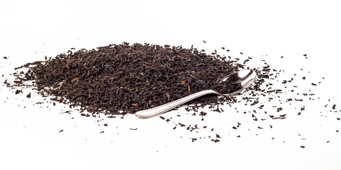 Dry black tea leaves with teaspoon isolated on white