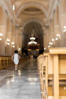 A little girl runs in the nave of a church, to the altar.