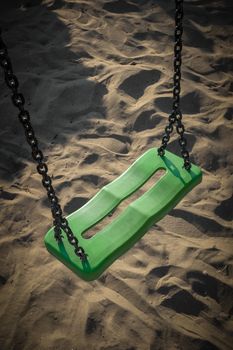 Swing on the beach to the sea, illuminated by the light of sunset.