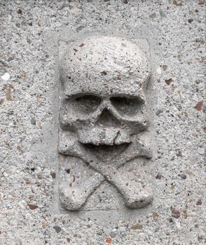 Skull with crossbones, bas-relief on a gravestone in stone. Ideal for death concept or events.