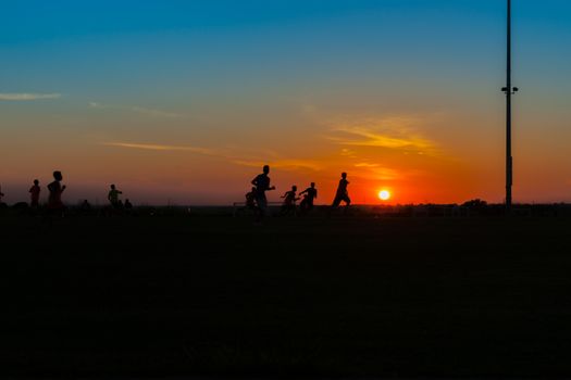 Young unrecognisable males practicing and training at soccer silhouetted at twilight