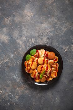 Trendy homemade breakfast, pancake cereal, mini pancakes on dark plate on grunge gray concrete background, leaves of lemon balm or peppermint and cherry jam. Space for text.