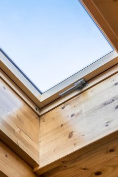 Skylight window in wooden house attic. Room with slanted ceiling made of natural eco materials. Environment friendly house.