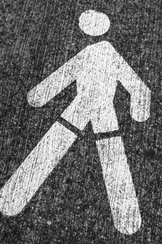 White Pedestrian Symbol on the gray asphalt. Roadsign.